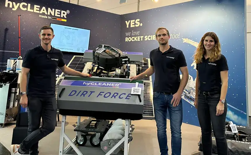 Three hyCLEANER employees are standing at a trade fair at a DIRT FORCE