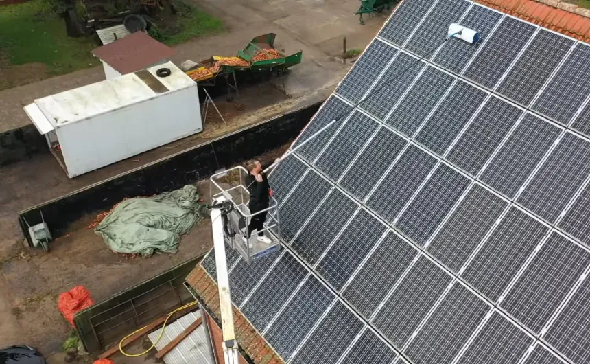 hyCLEANER employee on a lift platform cleans a PV system with a long hand brush