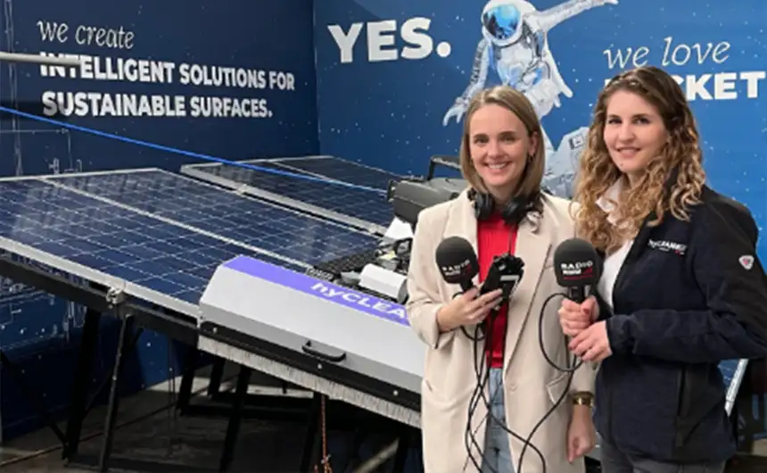 Zwei Personen mit Mikrofonen vor einem hyCleaner Informationsstand für einen Podcast