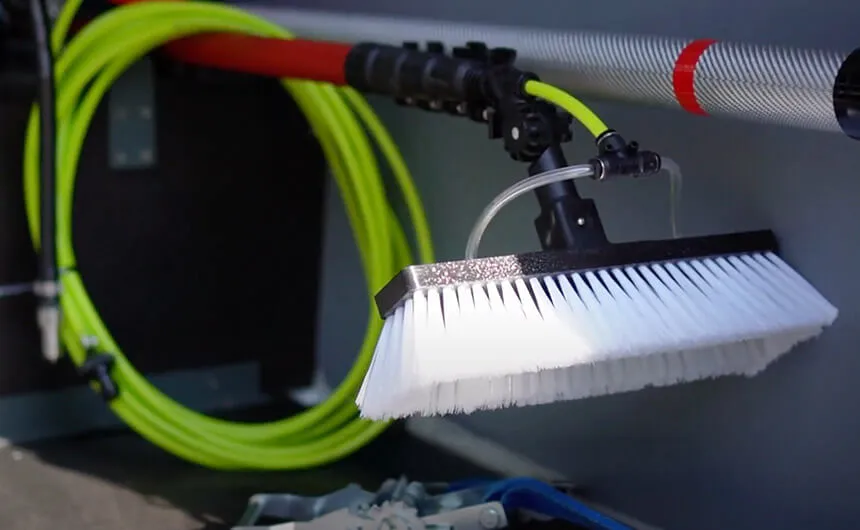 Une brosse manuelle avec un tuyau enroulé dans un support